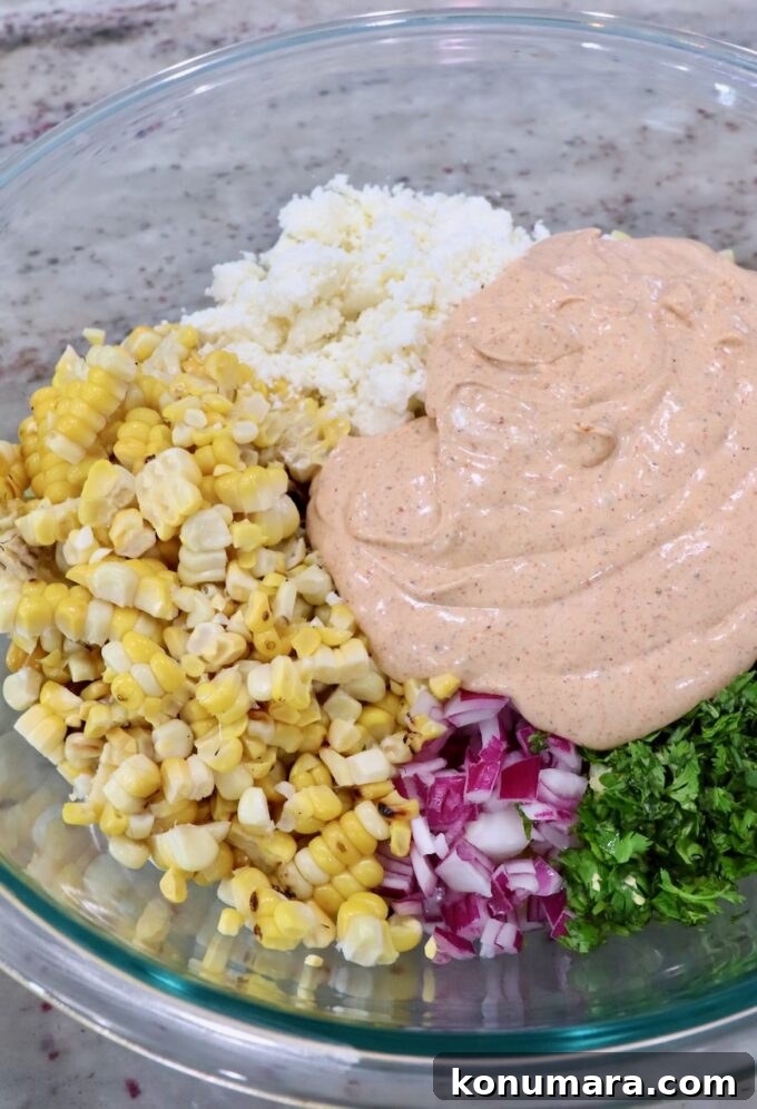 Elote Pasta Salad with Roasted Corn and Cotija 6 cooked pasta in large glass bowl with diced onions, cilantro, corn kernels, creamy dressing and cotija cheese