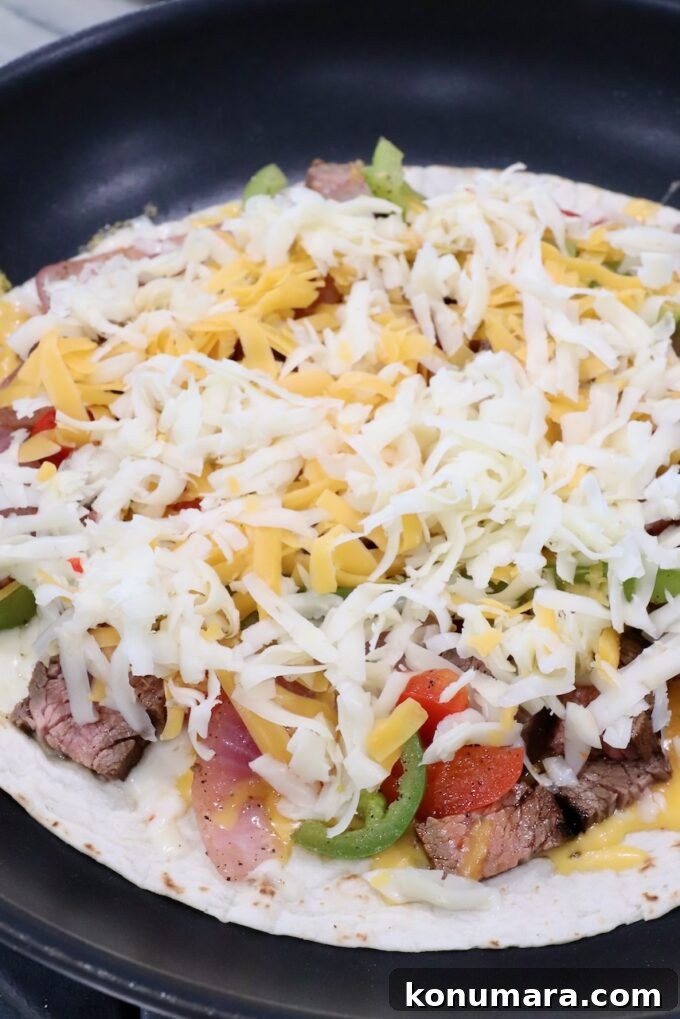 Steak Quesadillas Recipe with Melted Cheese and Salsa 8 shredded cheese on top of fajita veggies and grilled steak on tortilla in skillet