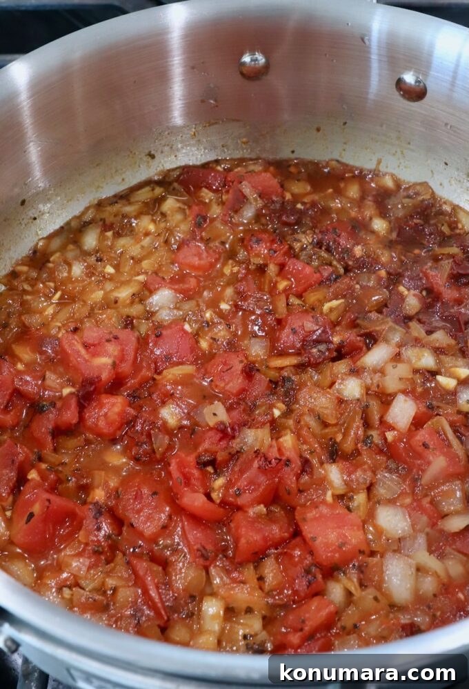 Smoky Chipotle Chicken Tinga Recipe 5 diced tomatoes in pan with diced onions, spices and chicken broth