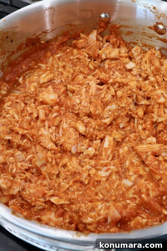 Smoky Chipotle Chicken Tinga Recipe 7 cooked, shredded chicken in tinga sauce in pan on the stove
