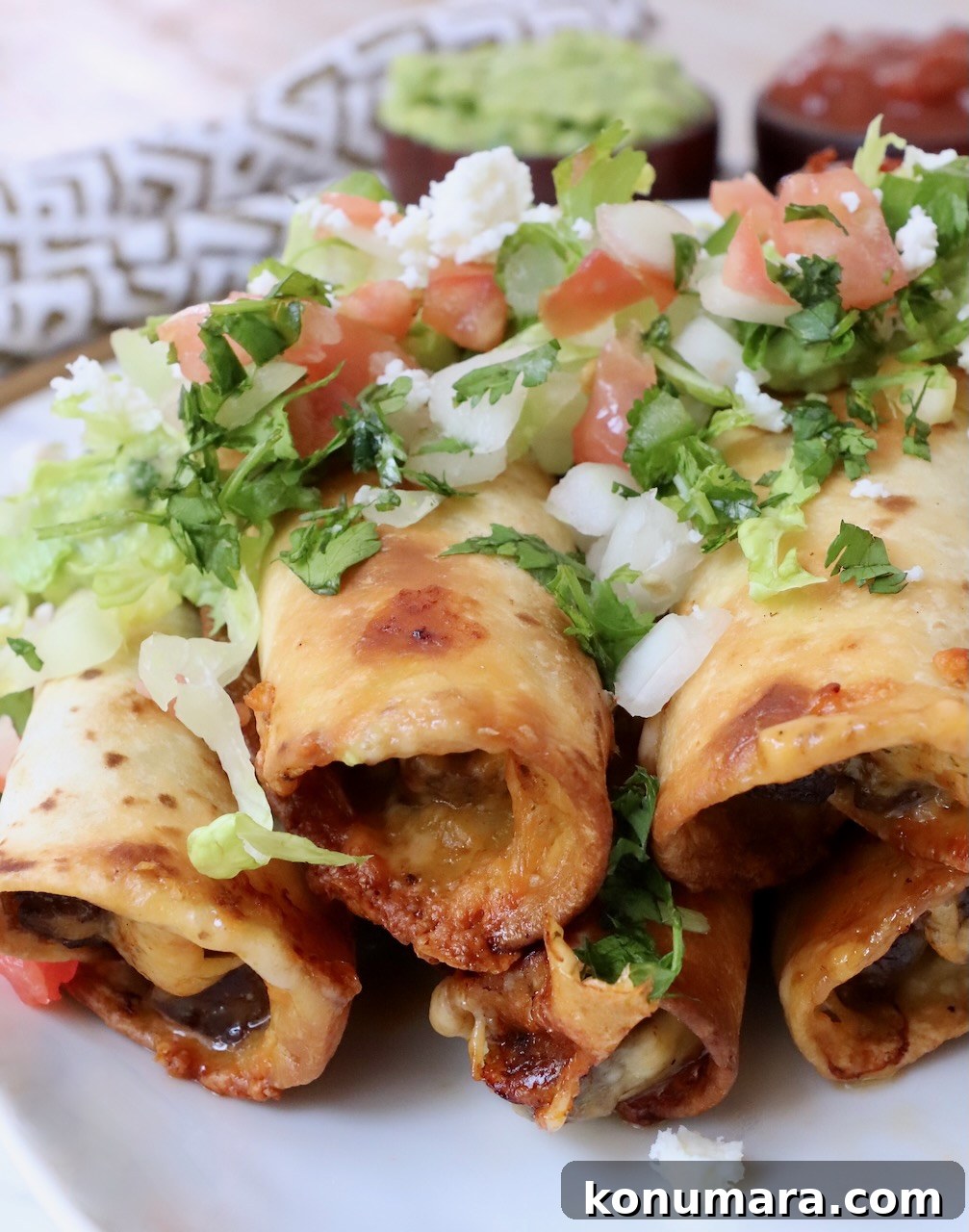 Homemade Crispy Beef Taquitos Recipe 2 beef taquitos stacked up on plate topped with pico de gallo