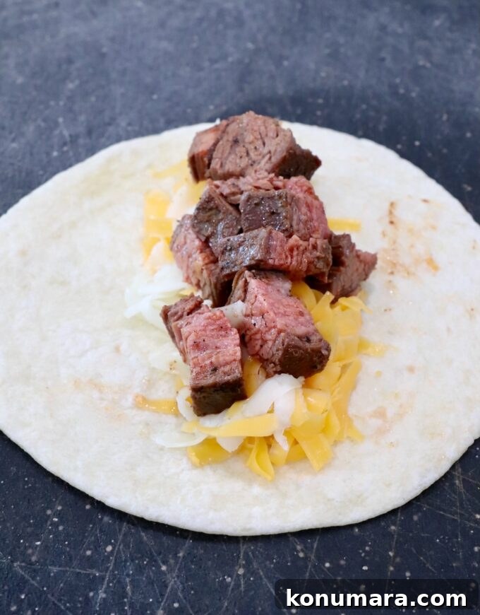 Homemade Crispy Beef Taquitos Recipe 6 tortilla on cutting board topped with shredded cheese and diced grilled steak