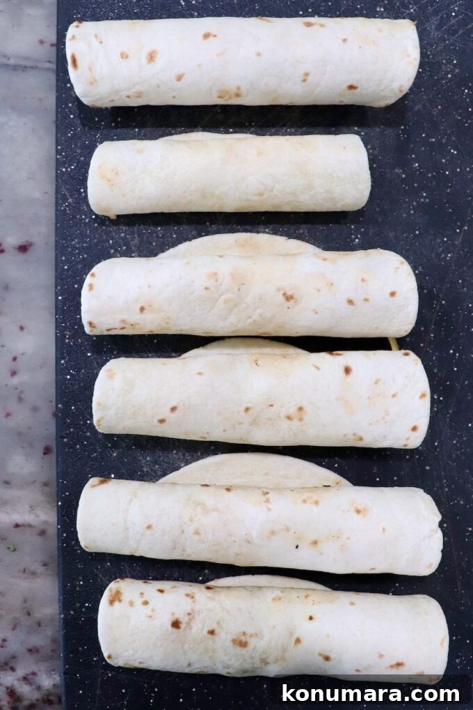 Homemade Crispy Beef Taquitos Recipe 7 rolled up uncooked taquitos on cutting board