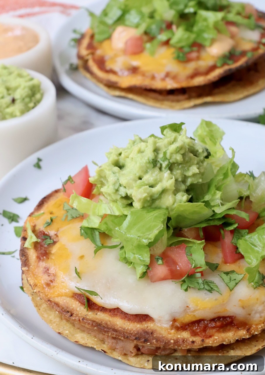 Mexican pizza on plate topped with shredded lettuce and guacamole