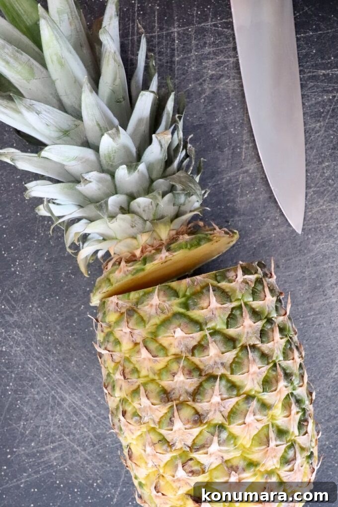 fresh pineapple with the crown cut off of the top on a cutting board