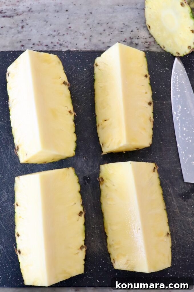 fresh pineapple sliced into four pieces on a cutting board