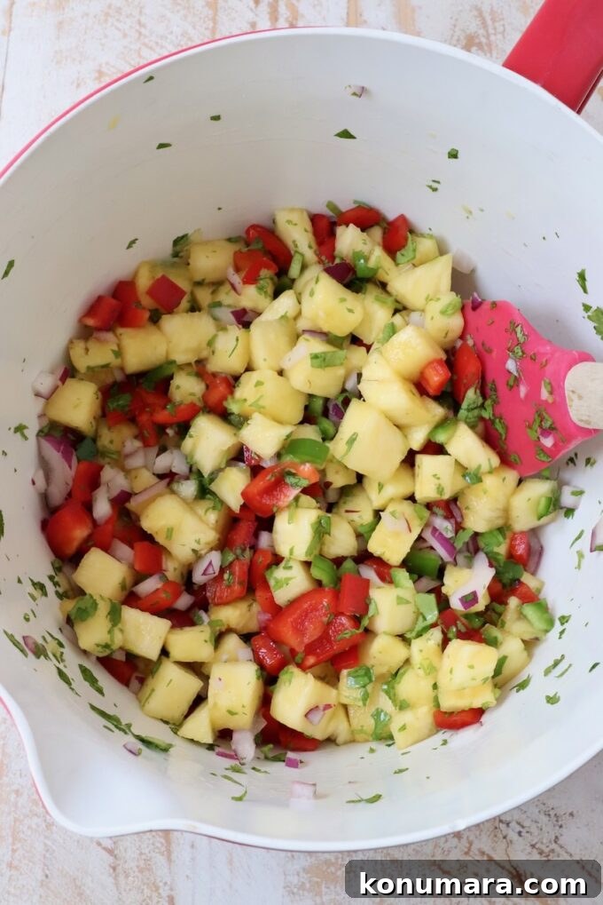 pineapple salsa in a large mixing bowl with a spatula