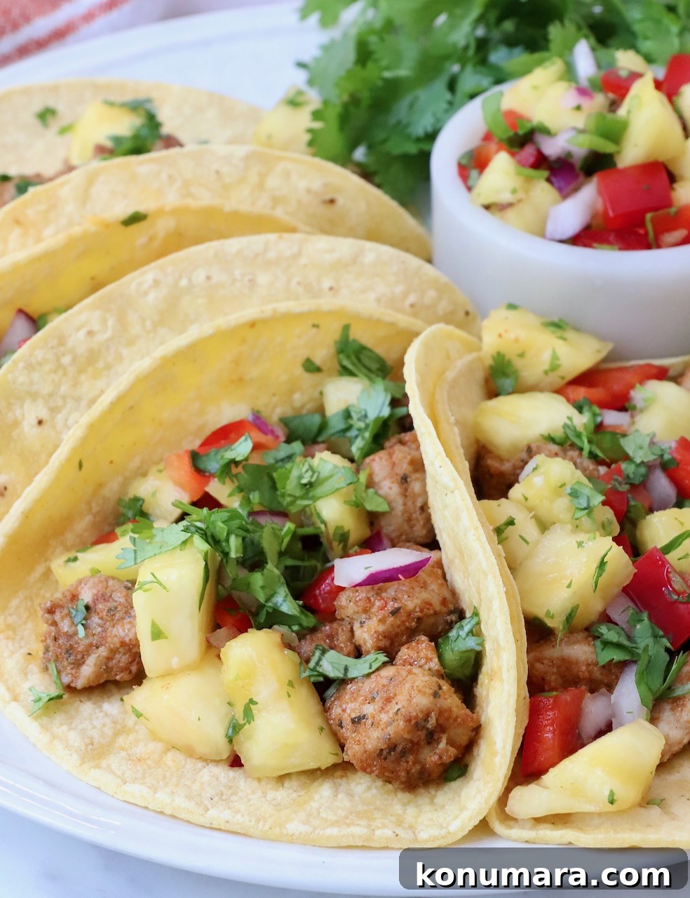 Homemade Carnitas Tacos Recipe with Salsa Verde 2 pork tacos topped with pineapple salsa on a plate