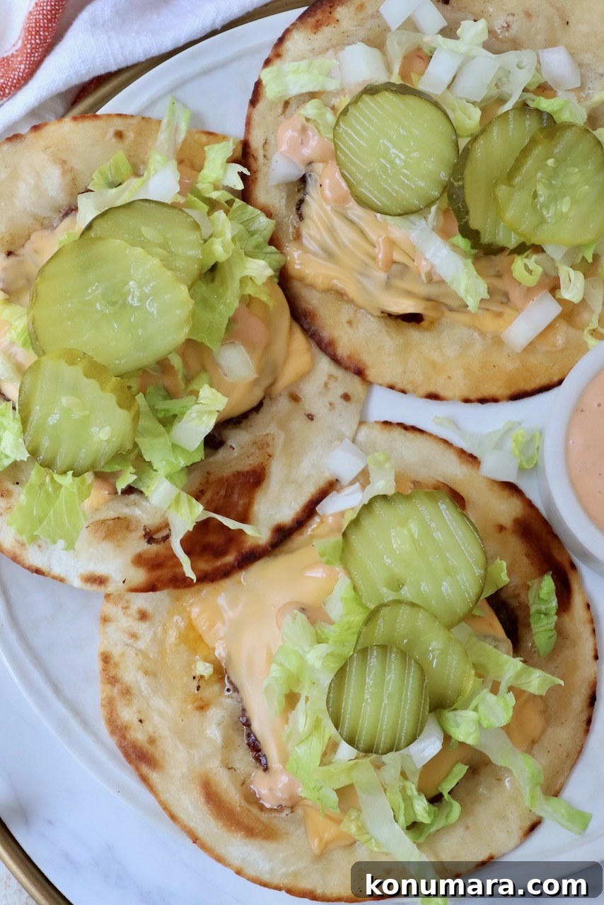 Smash Burger Taco Recipe: Crispy Smashed Patties 2 Smash burger tacos on a plate topped with sliced pickles