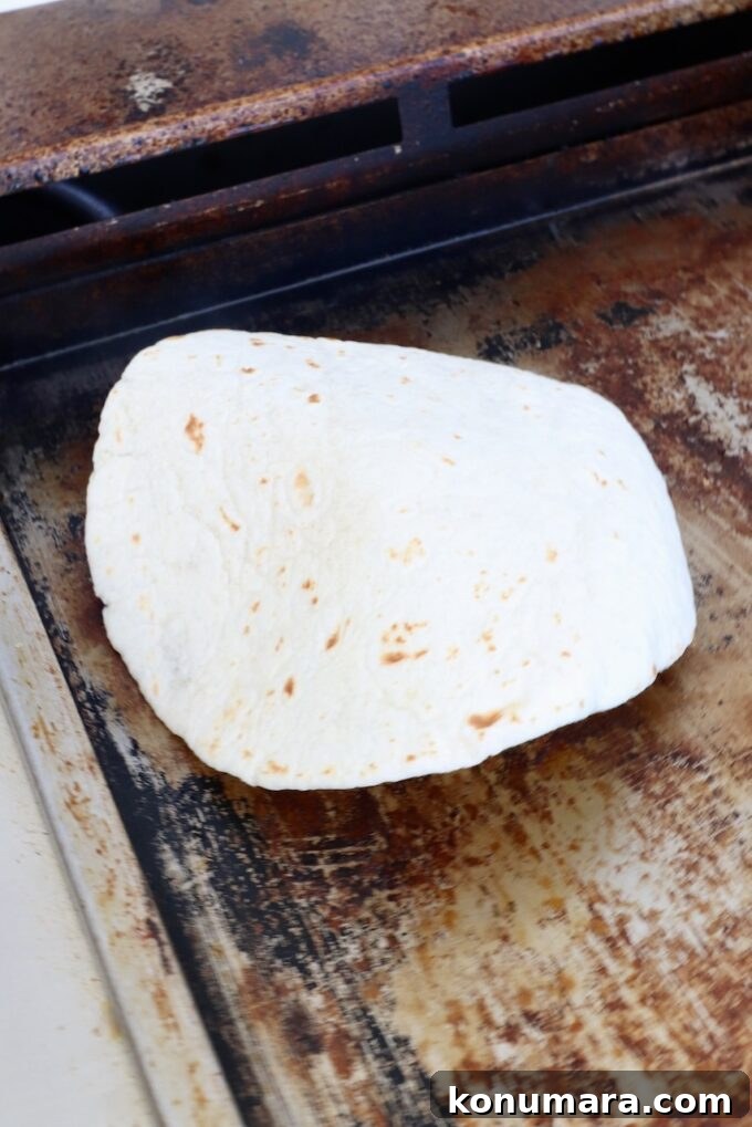 Smash Burger Taco Recipe: Crispy Smashed Patties 5 Tortilla on top of a ball of beef on a griddle