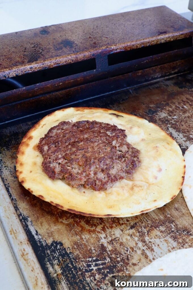 Smash Burger Taco Recipe: Crispy Smashed Patties 8 Cooked burger patty on a tortilla on a griddle