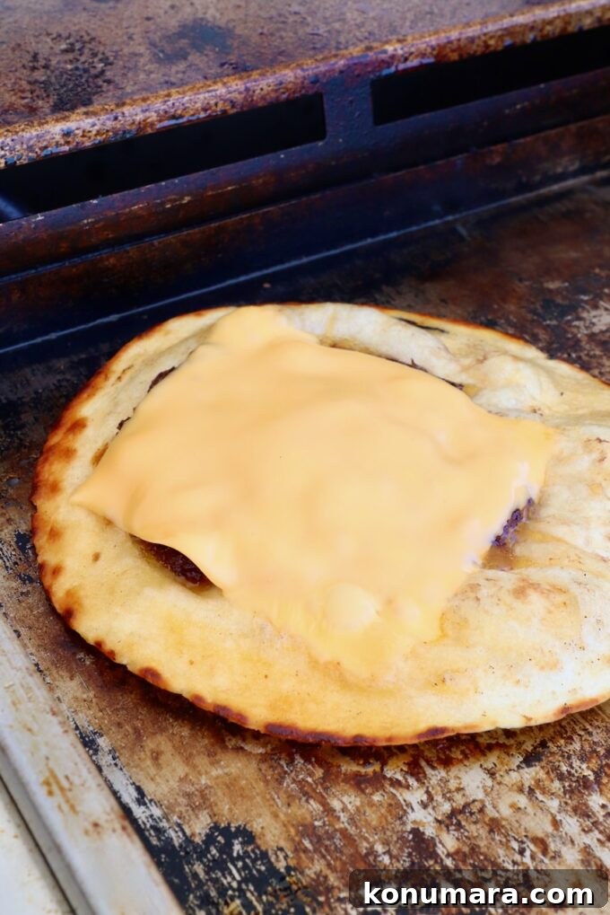 Smash Burger Taco Recipe: Crispy Smashed Patties 9 Burger patty topped with a slice of cheese on a tortilla on a griddle