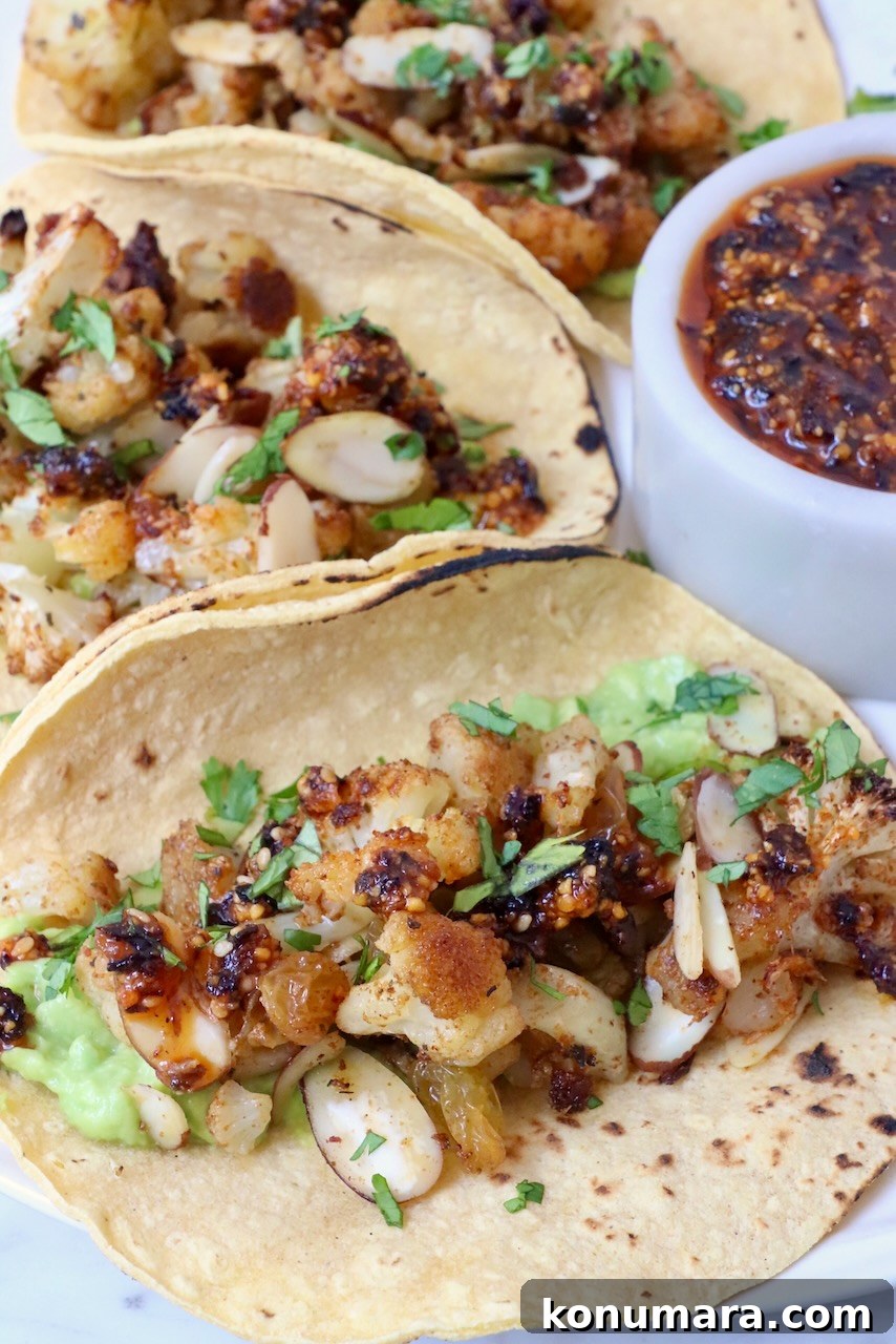 cauliflower tacos on a plate with a small bowl of salsa on the side