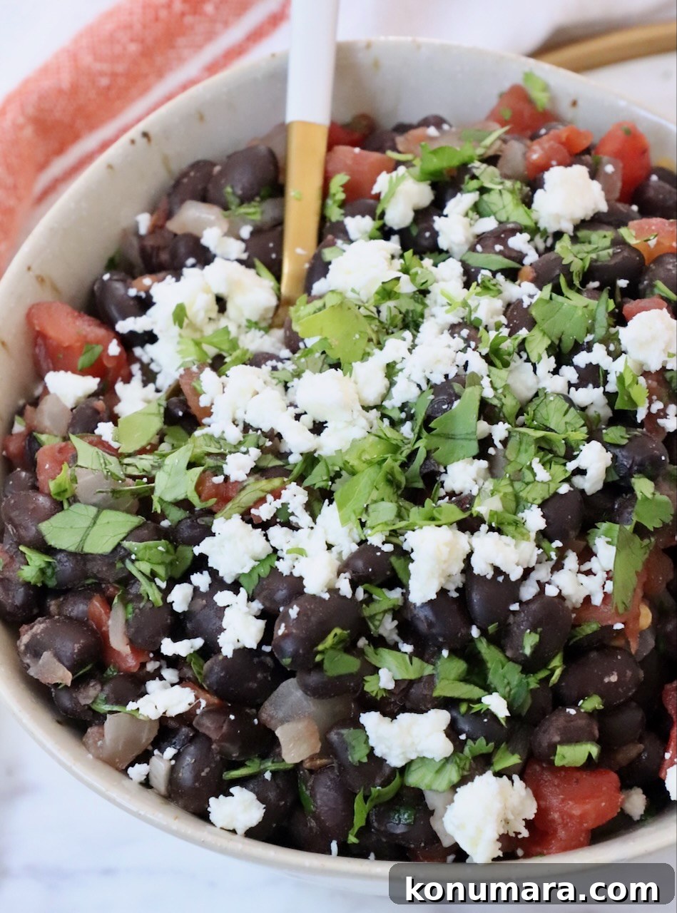black beans in bowl topped with crumbled cheese and chopped cilantro