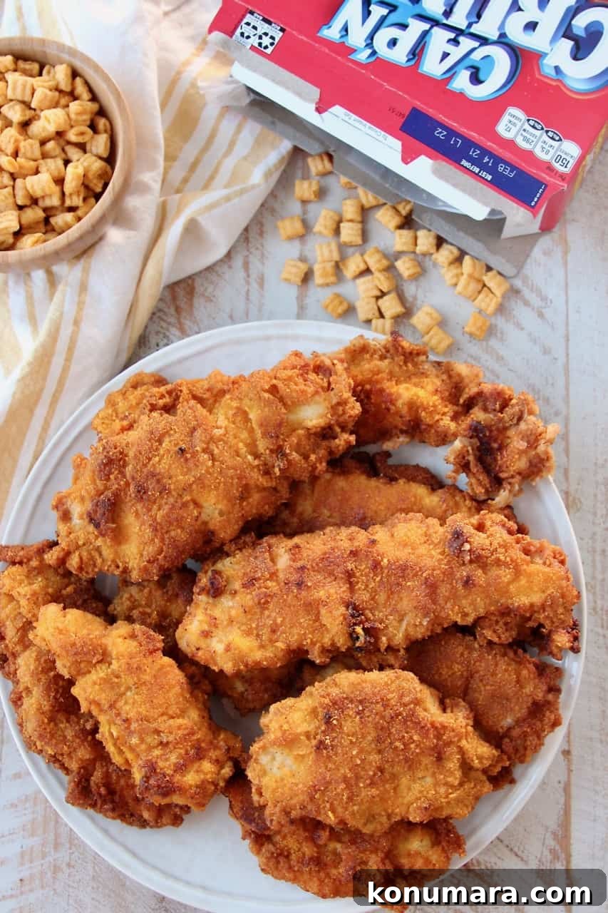 Dad's Famous Captain Crunch Chicken Tenders Recipe 2 Fried chicken stacked up on plate with box of Cap'n Crunch cereal next to the plate