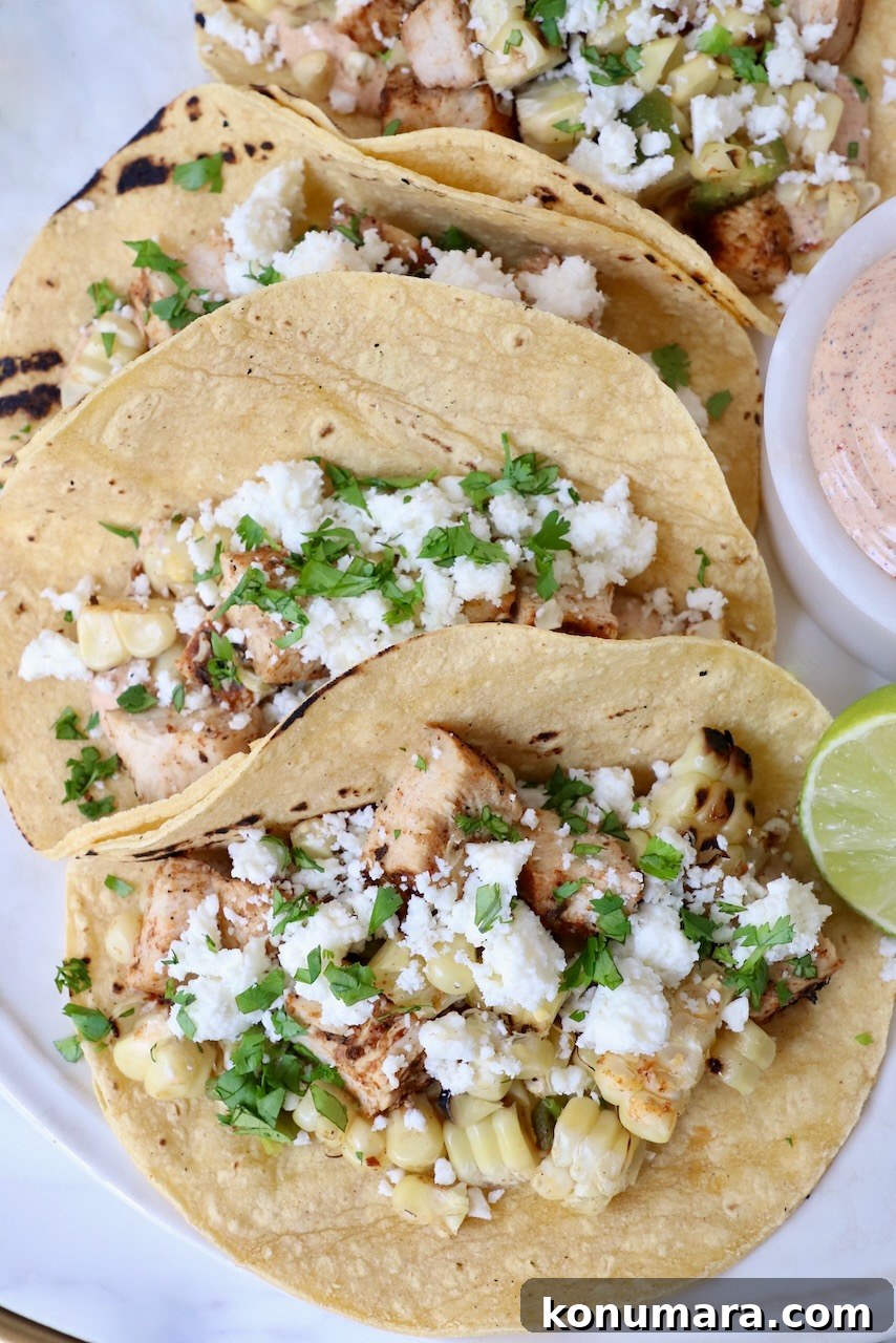 Elote Chicken Tacos with Mexican Street Corn 11 street corn and chicken tacos on plate with lime wedge