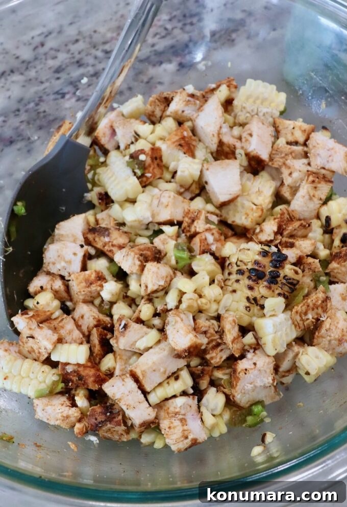 Elote Chicken Tacos with Mexican Street Corn 9 diced grilled chicken, corn kernels and diced jalapenos in glass bowl with mixing spoon