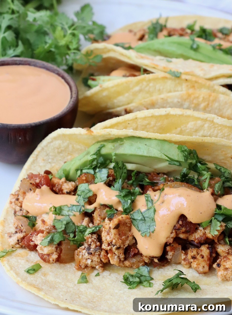 tacos on plate filled with crumbled tofu, chipotle sauce and avocado slices
