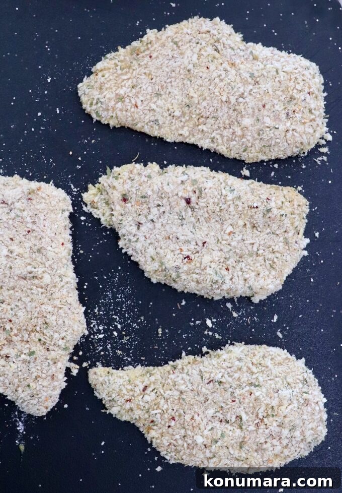 Crispy Parmesan-Crusted Chicken Recipe 10 breadcrumb coated chicken breasts on a cutting board