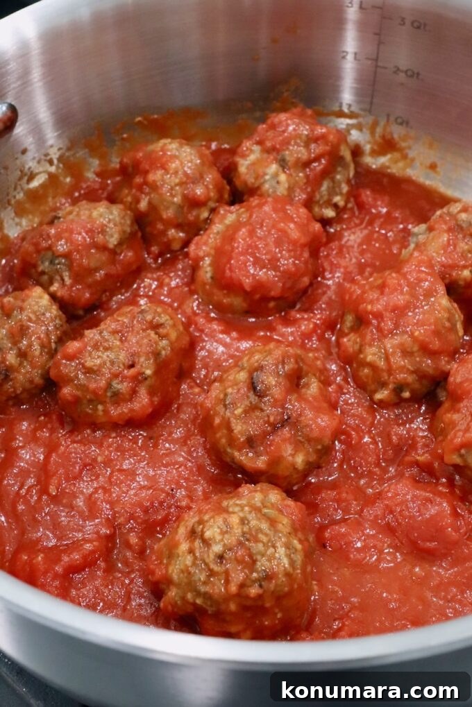 Classic Meatball Sub Recipe with Marinara and Mozzarella 4 meatballs in marinara sauce in pan on the stove