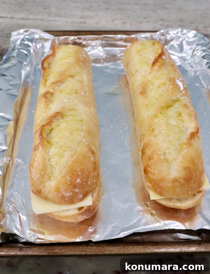 Classic Meatball Sub Recipe with Marinara and Mozzarella 6 baguettes filled with mozzarella cheese on foil lined baking sheet