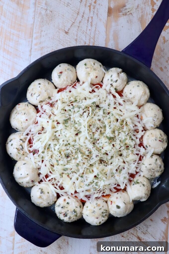 pizza dip in the middle of a skillet surrounded by balls of dough