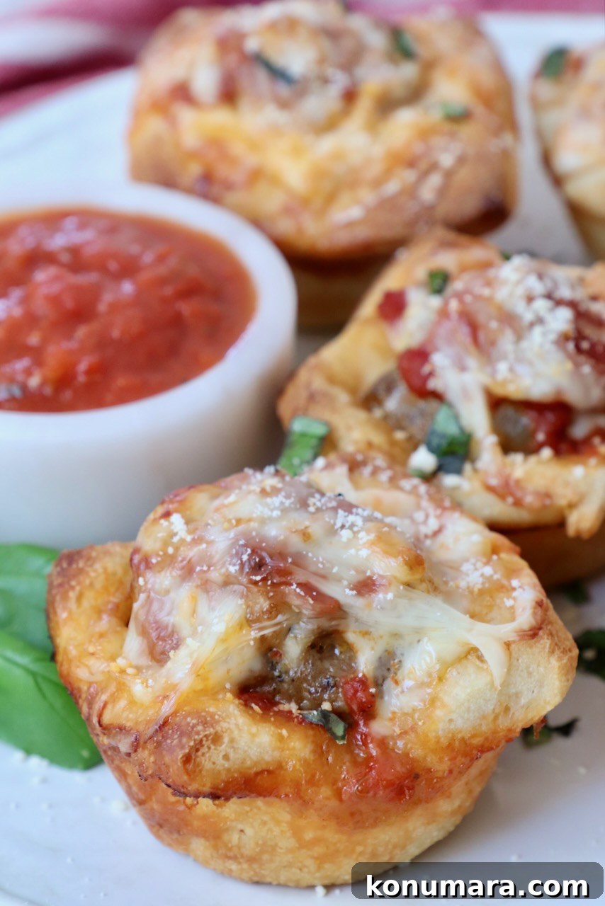 cooked meatball sub bites on a plate with a small bowl of marinara sauce