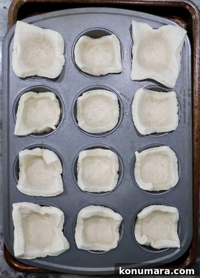 pizza dough squares pressed into a muffin tin