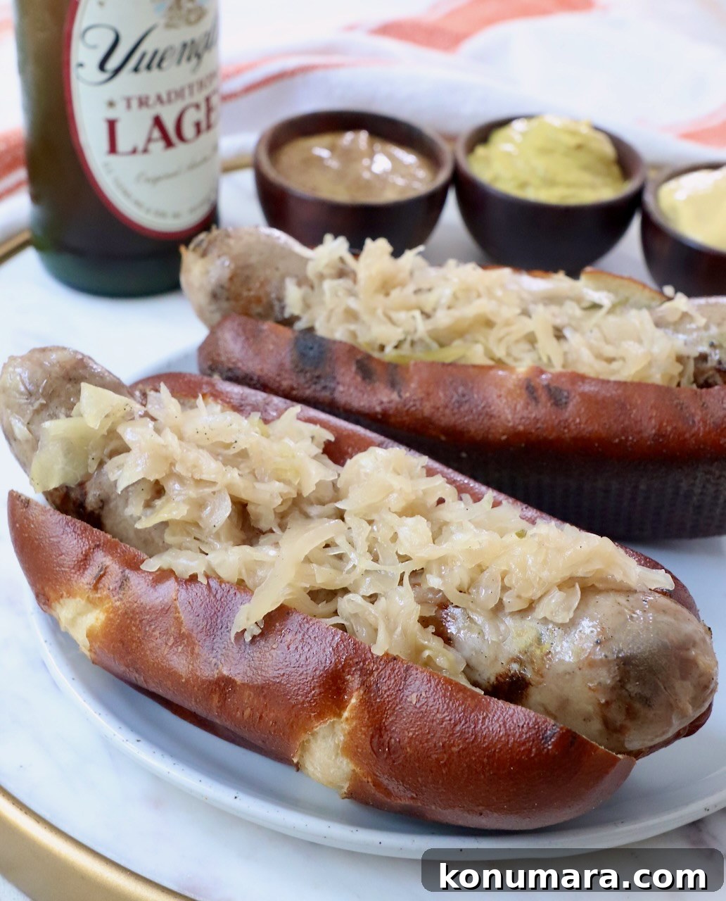 Smoky Grilled Bratwurst with Caramelized Onions 2 grilled bratwurst and sauerkraut on pretzel bun on plate