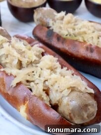 grilled bratwurst in a bun topped with sauerkraut on a plate
