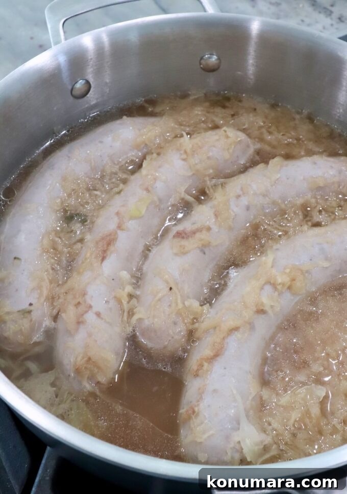 Smoky Grilled Bratwurst with Caramelized Onions 5 cooked bratwurst in pan with beer and sauerkraut