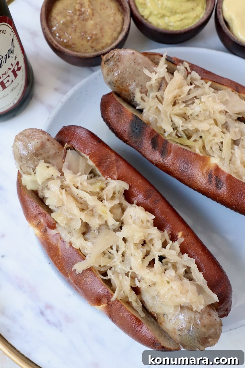 Smoky Grilled Bratwurst with Caramelized Onions 8 grilled bratwurst in pretzel bun topped with sauerkraut on a plate
