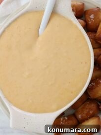 beer cheese dip in bowl with spoon, with pretzel bites on the side of the bowl