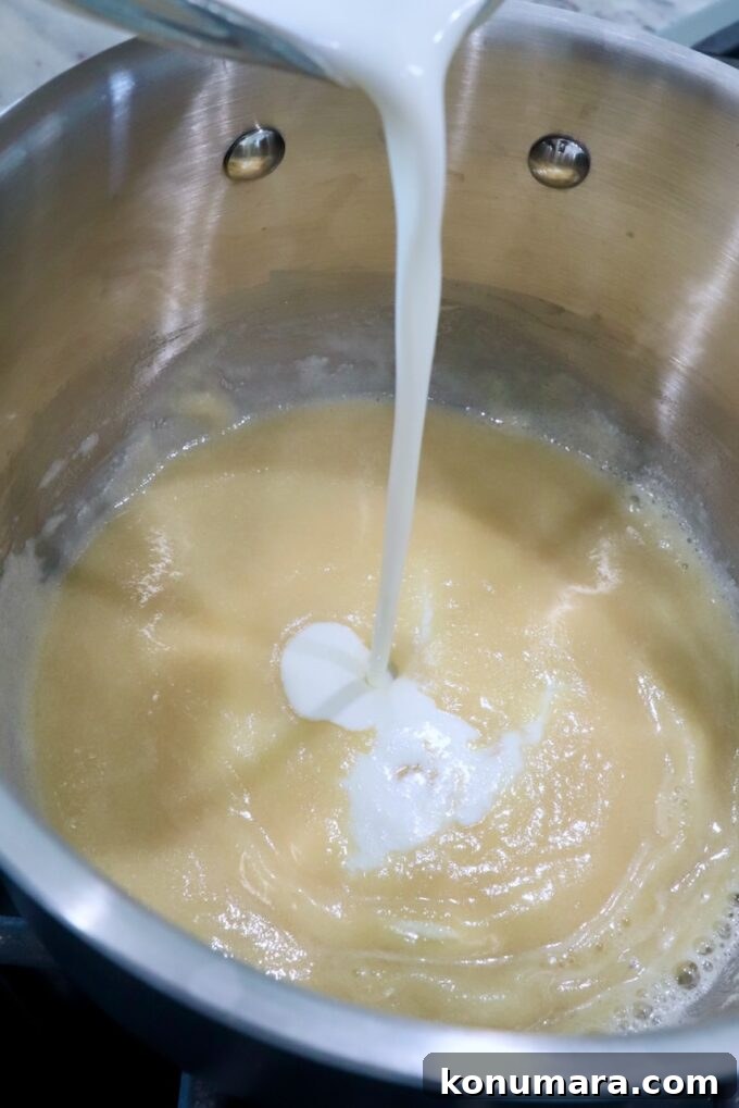 heavy cream poured into a roux in a pot on the stove
