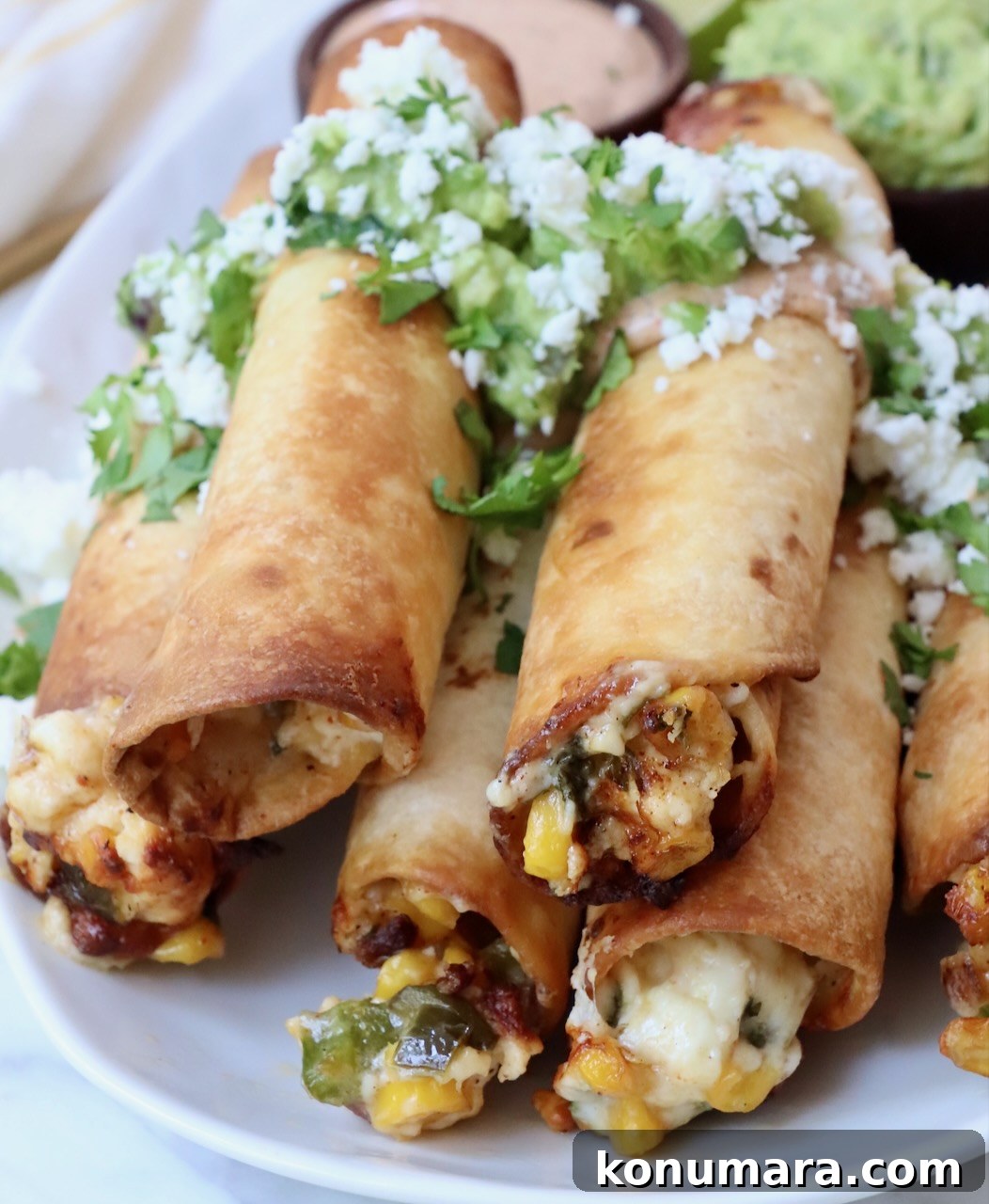 taquitos stacked up on a plate filled with cheese and corn