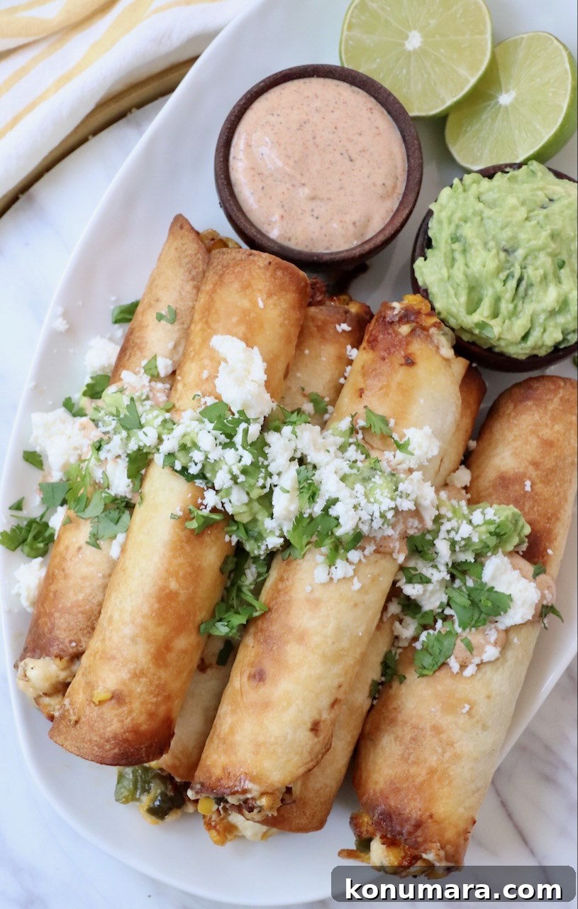cooked taquitos stacked up on a plate topped with guacamole, cheese and cilantro