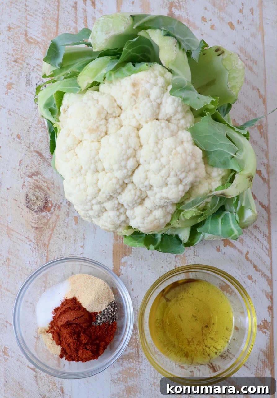 head of cauliflower next to small bowl of spices and small bowl of oil