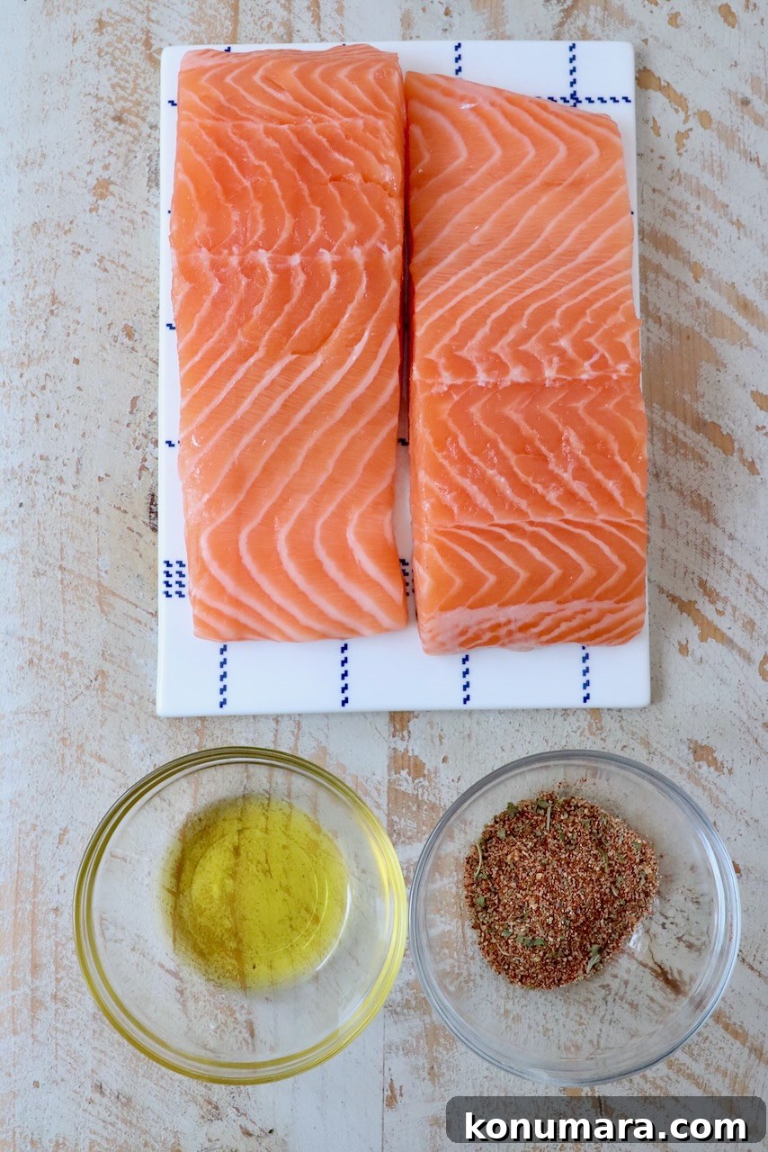 Crispy Air Fryer Salmon with Lemon Garlic Butter 3 salmon filets next to small bowl of seasoning and small bowl of oil