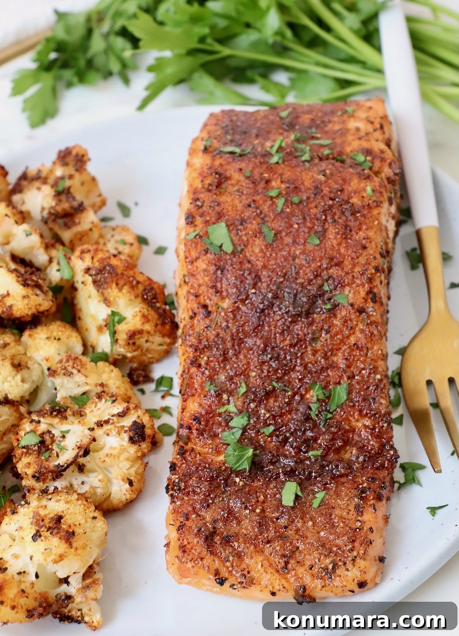 Crispy Air Fryer Salmon with Lemon Garlic Butter 5 cooked, seasoned salmon on a plate with roasted cauliflower and a fork