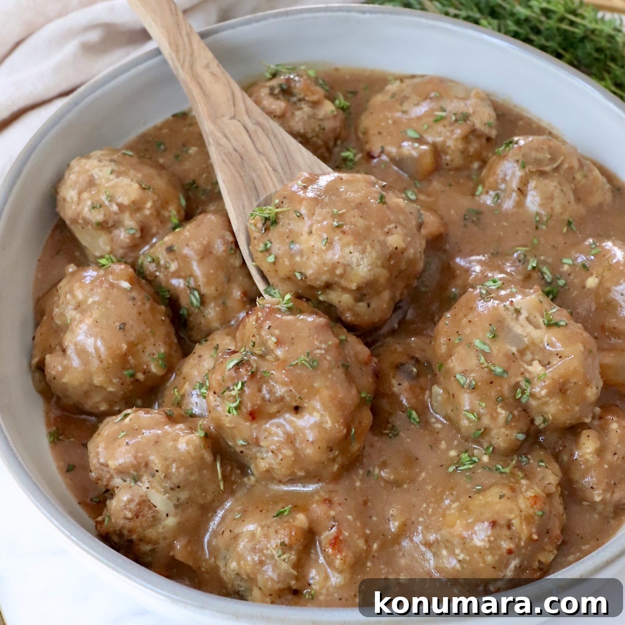 meatballs in gravy in a bowl with a spoon