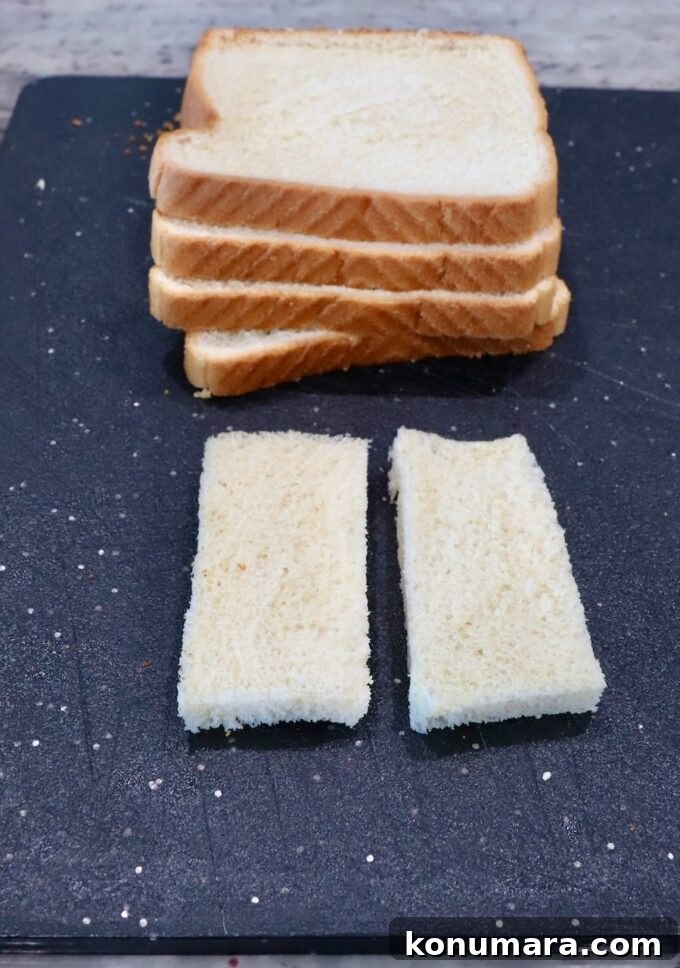 Crispy Bacon Roll Ups with Cream Cheese and Chives 4 white bread stacked up on a cutting board with one piece sliced in half with the crusts removed
