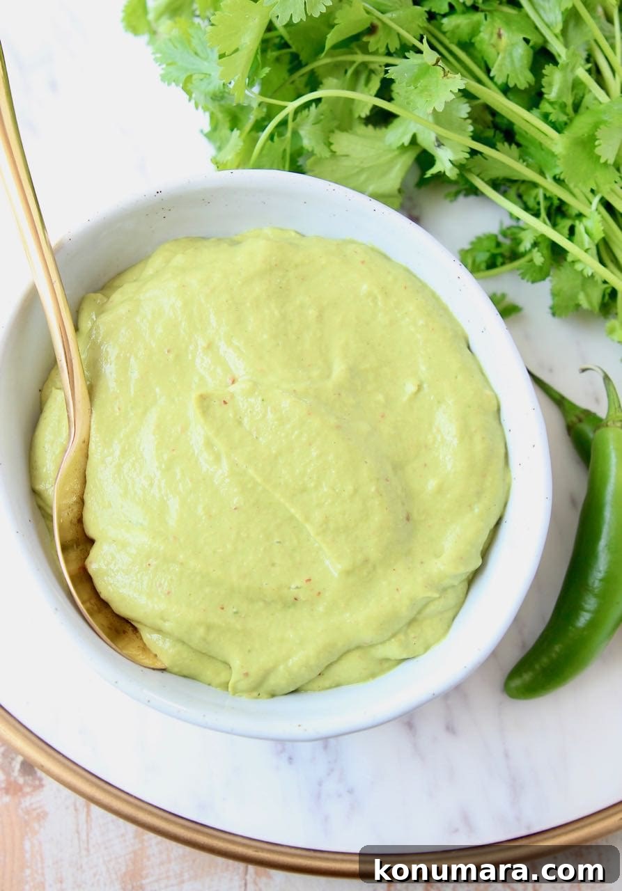 Creamy avocado sauce in bowl with gold spoon