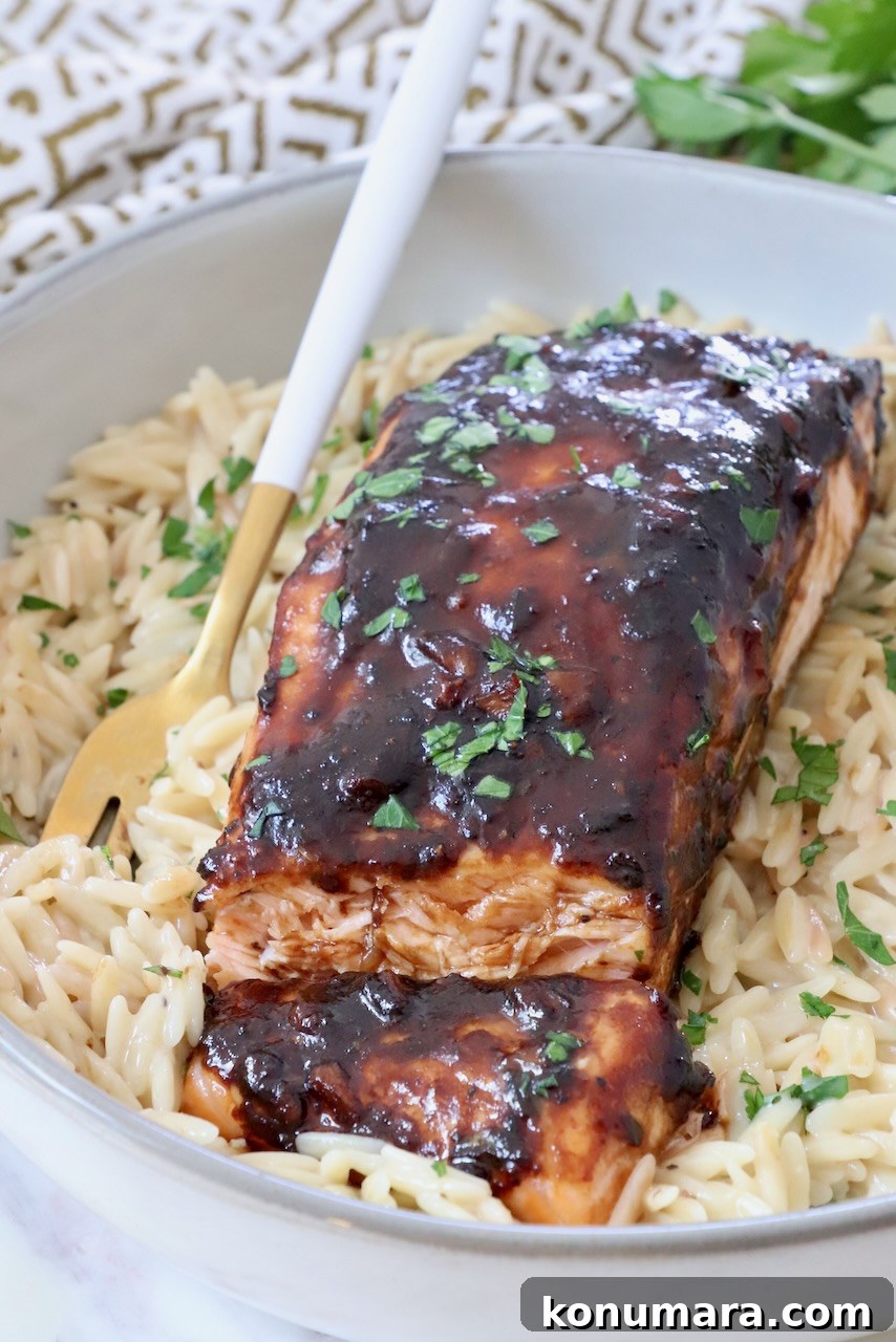 cooked balsamic glazed salmon on a bed of orzo in a bowl with a fork