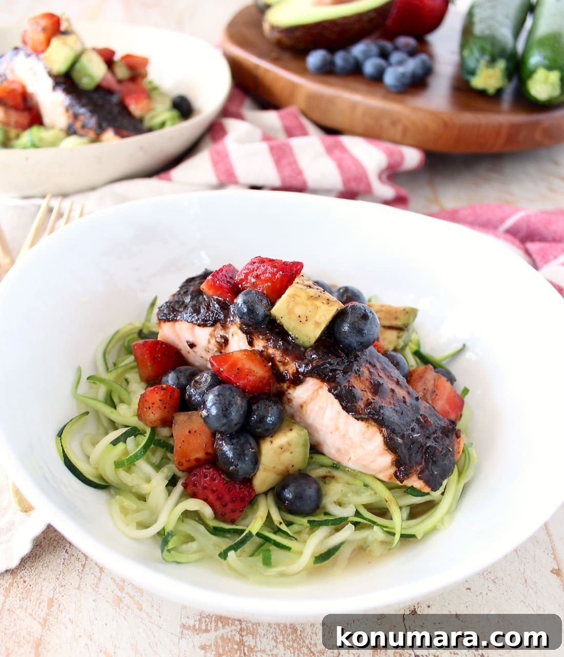 Roasted balsamic salmon is served over zucchini noodles topped with a berry avocado salsa for a flavorful meal that's easy to make, gluten free, dairy free and Whole 30 approved!