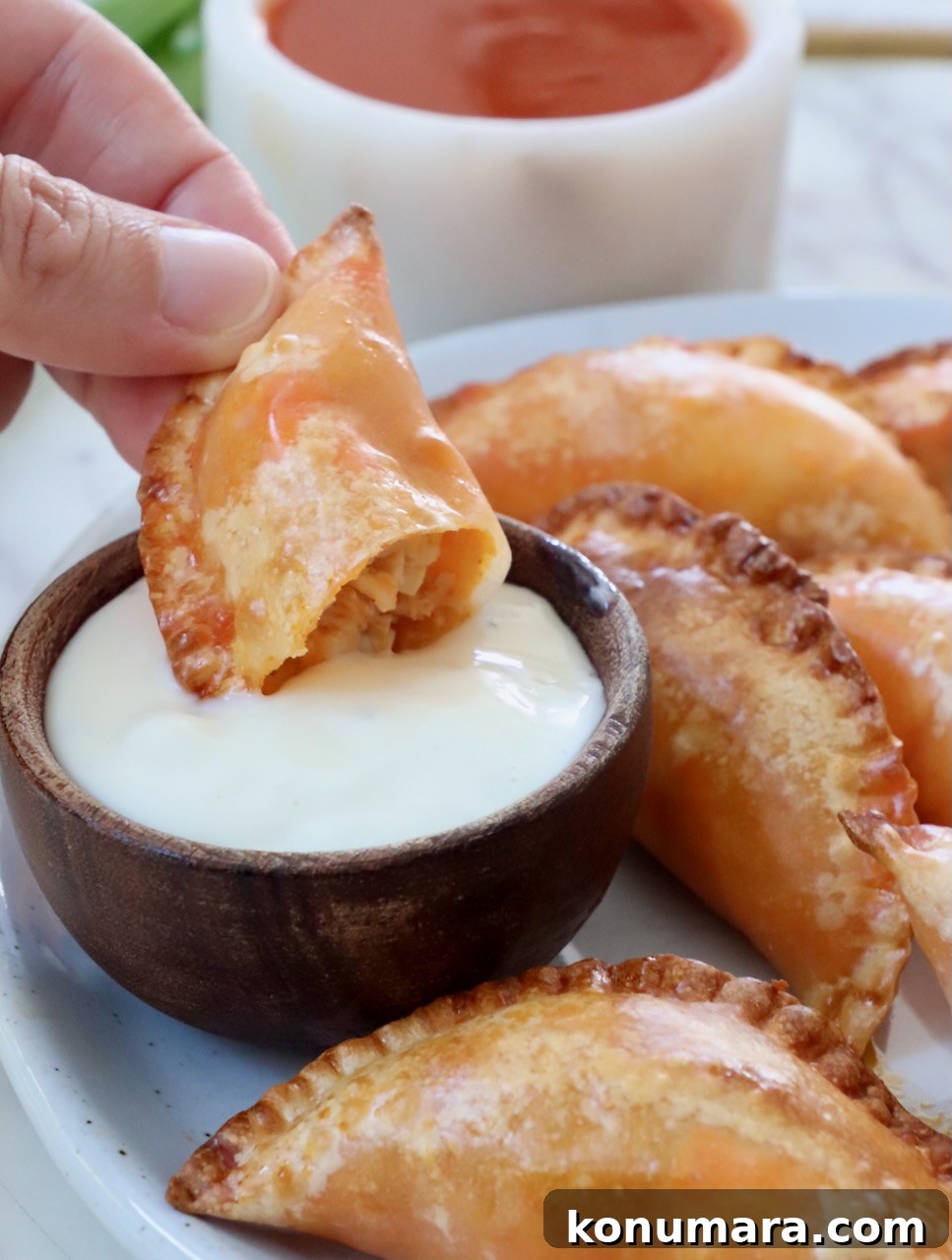 Crispy Buffalo Chicken Bites Recipe with Blue Cheese Dip 2 hand dipping a buffalo chicken bite in a small bowl of blue cheese dressing