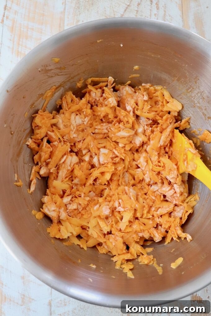 Crispy Buffalo Chicken Bites Recipe with Blue Cheese Dip 4 shredded chicken tossed with buffalo sauce in a bowl with a spatula