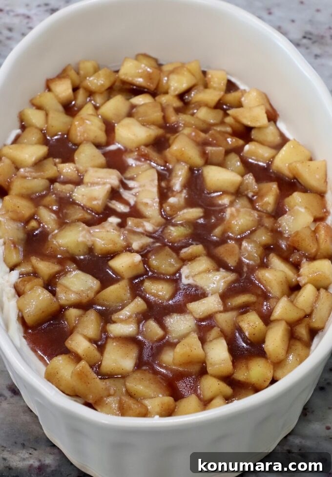 Apple pie filling on top of cream cheese in a casserole dish