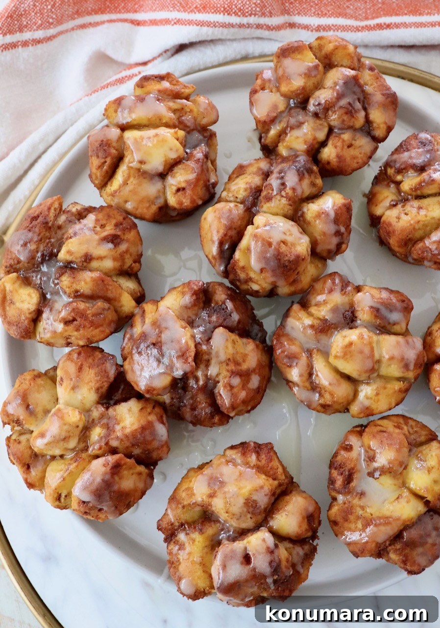 Maple-Glazed Pull-Apart Pumpkin Cinnamon Rolls 10 pull apart pumpkin cinnamon rolls on a plate drizzled with cream cheese icing