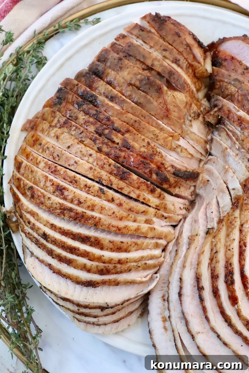 Smoked Turkey Recipe for Thanksgiving: Juicy, Crispy Skin 11 sliced turkey breast on a plate with fresh herbs