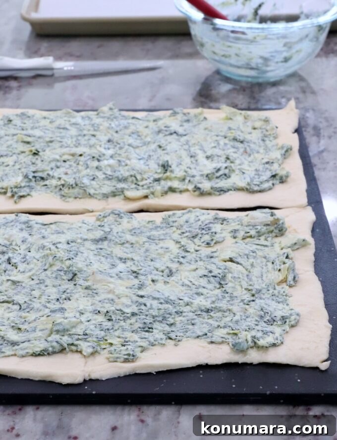 Spinach Pinwheels: Savory Appetizer Recipe 4 spinach artichoke dip spread on crescent roll dough on a cutting board